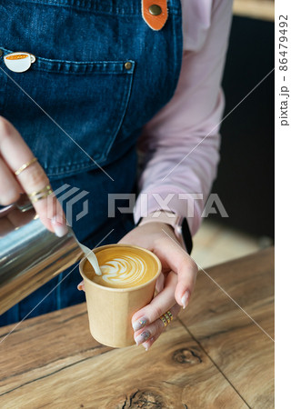 The process of making a barista cappuccino with a beautiful pattern on the foam in an eco-craft glass. Coffee to go concept. 86479492