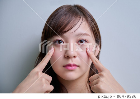 両目を指差ししている若い女性 86479536