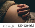 Pregnant woman touching her hand to her belly. 86480468