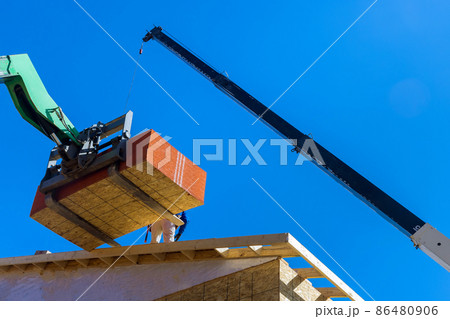 Builders are working on the roof covering it with plywood layer using professional hydraylic platform 86480906