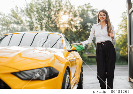 Business woman wearing on a white shirt and black trousers wiping rearview car mirror 86481265