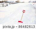 Close up of big red plastic showel in the process of removing snow in winter 86482613