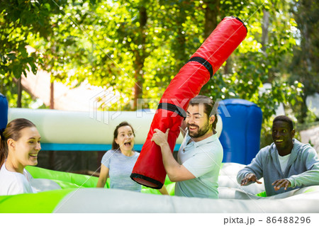 Funny friends playing on an inflatable trampoline in an amusement park 86488296