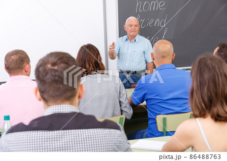Elderly teacher standing in front of students 86488763