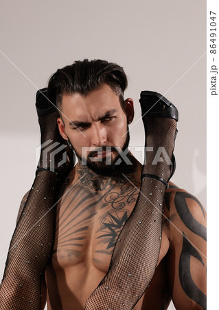 Confident tattooed man with female legs on shoulders Confident tattooed man with female legs on shoulders 86491047