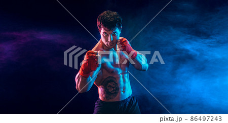 Half length muscular kickbox or muay thai fighter who punching on smoke background. Sport concept. 86497243