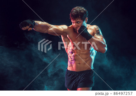 Half length of muscular boxer who training and practicing jab on smoke background. Sport concept 86497257