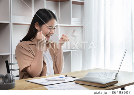 Joyful, Surprised or shocked Asian woman raised her arms all the way because she did a good job the boss gave her a big bonus making her very happy, Raise your hand, Smiling and screaming for success. 86498607