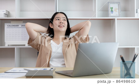 Young Asian female employee is doing a relaxing posture after a hard Midday's work, Happy women resting at work after work is finished, Fatigue is eased, Women working at home, Relax. 86498610