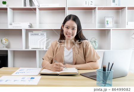 Asian woman taking notes in notebook while studying online in laptop at home, Video chat, Online communication , Stay home, New normal, Distance learning , Social distancing, Learn online. Asian woman taking notes in notebook while studying online in laptop at home, Video chat, Online communication , Stay home, New normal, Distance learning , Social distancing, Learn online. 86499082
