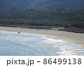 波打ち際を歩くサーファー 86499138