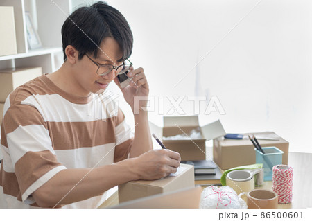 Asian man is taking online orders from a phone and chatting with customers to confirm their order, Selling products online or doing freelance work at home, Working at home and owning businesses. Asian man is taking online orders from a phone and chatting with customers to confirm their order, Selling products online or doing freelance work at home, Working at home and owning businesses. 86500601