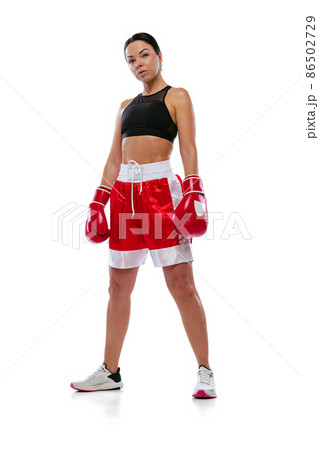 Portrait of young beautiful girl, professional boxer in boxing shorts and gloves posing isolated on white studio background. Concept of sport, studying, competition 86502729