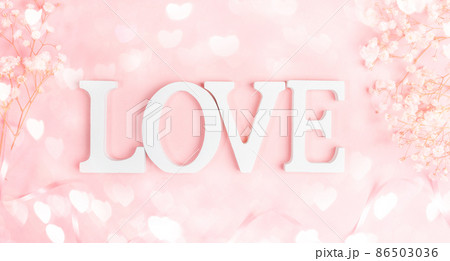 White letters LOVE with frame of gentle white gipsofila on pastel pink with bokeh lights hearts. Festive Valentine's Day, Mother's Day, Women's Day, March 8t greeting card. Top view, flat lay. 86503036
