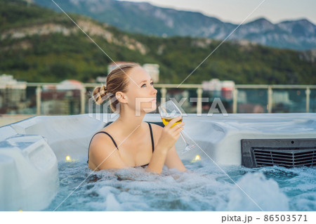 Portrait of young carefree happy smiling woman relaxing at hot tub during enjoying happy traveling moment vacation life against the background of green big mountains 86503571