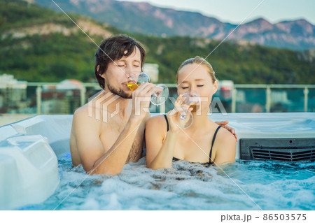 Portrait of young carefree happy smiling couple relaxing at hot tub during enjoying happy traveling moment vacation life against the background of green big mountains 86503575