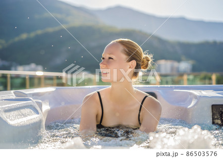 Portrait of young carefree happy smiling woman relaxing at hot tub during enjoying happy traveling moment vacation life against the background of green big mountains 86503576