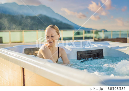 Portrait of young carefree happy smiling woman relaxing at hot tub during enjoying happy traveling moment vacation life against the background of green big mountains 86503585