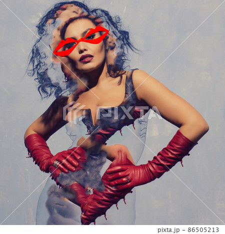 Asian woman posing in black leather dress and red gloves with red glasses lips shape on face Asian woman posing in black leather dress and red gloves with red glasses lips shape on face 86505213