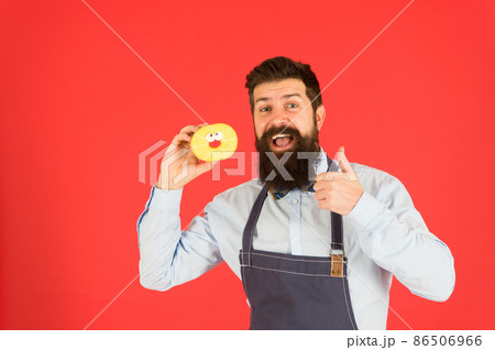 Bearded well groomed man in apron selling donuts. Bearded well groomed man in apron selling donuts. 86506966
