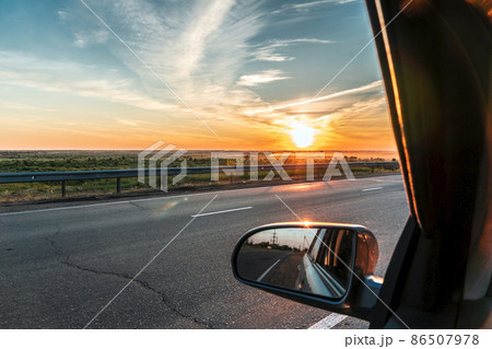 Evening trip to travel on the highway by car at sunset sunrise in the golden hour. Heavenly light.Dramatic evening sky with clouds and rays of the sun view from the window.Panoramic view of clouds 86507978