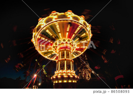 Colorful chain swing carousel in motion at amusement park at night. Colorful chain swing carousel in motion at amusement park at night. 86508093
