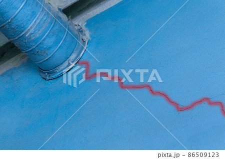 Crack on the old blue broken plaster wall of damage near the ventilation pipe of the industrial plant 86509123