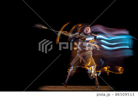 Dynamic portrait of brutal serious man, medieval knight with swinging ax fighting isolated over dark background in neon mixed light. Art, history, creativity 86509513
