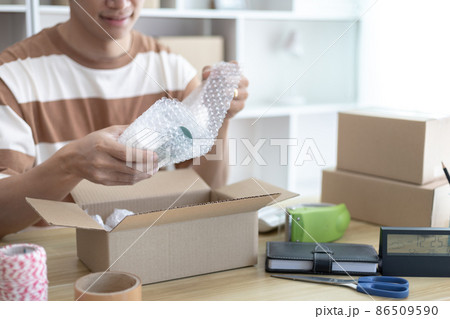 Man is packing in the mailbox to prepare to deliver it to the customer, Working at home and owning businesses, Online shopping SME entrepreneur, packing box, Sell online, freelance working. Man is packing in the mailbox to prepare to deliver it to the customer, Working at home and owning businesses, Online shopping SME entrepreneur, packing box, Sell online, freelance working. 86509590