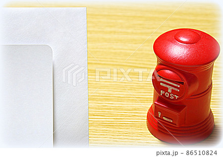 【イラスト風】木目の机に置いた郵便ポスト形の貯金箱と礼状の封筒（コピースペース有り） 86510824