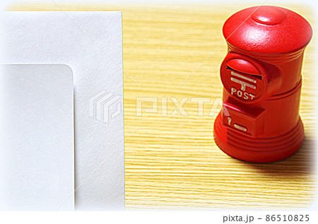 【イラスト風】木目の机に置いた郵便ポスト形の貯金箱と礼状の封筒（コピースペース有り） 86510825