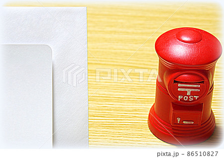 【イラスト風】木目の机に置いた郵便ポスト形の貯金箱と礼状の封筒（コピースペース有り） 86510827