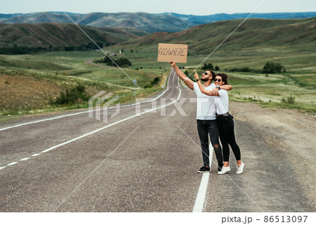 A man and a woman are hitchhiking. A young couple goes hitchhiking around the country. Free hitchhiking trip. A lover who travels free by hitchhiking. The couple goes traveling. Copy space 86513097