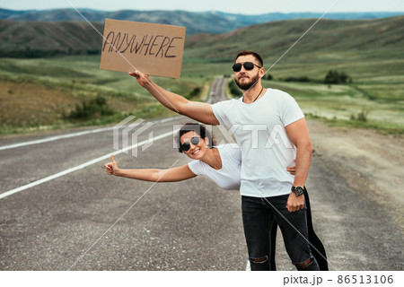 A couple hitchhiking. A man and a woman catch a car by the road. A young couple votes on the road. A man and a woman are hitchhiking. A couple hitch a ride on the road. Hitching a ride A couple hitchhiking. A man and a woman catch a car by the road. A young couple votes on the road. A man and a woman are hitchhiking. A couple hitch a ride on the road. Hitching a ride 86513106