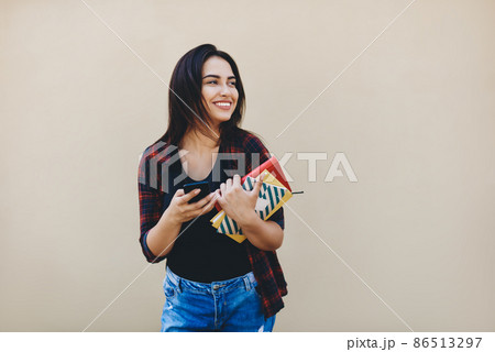 Happy woman with notebook against beige wall Happy woman with notebook against beige wall 86513297