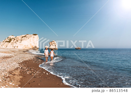 Happy couple holding hands walking on the sandy beach. Couple in love at sunset by the sea. Couple in love on vacation. Travel vacation concept. Romantic couple enjoying a beach walk at sunset 86513548