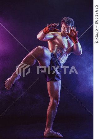 Full size of Muay thai fighter who delivering knee hit isolated on smoke background. mixed media  86513625