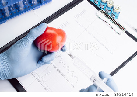 Genetically modified organism. GMO scientist injecting liquid from syringe into red tomato. Gmo food biotechnology concept. 86514414