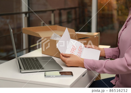 Woman with note Free Delivery working at table indoors, closeup. Courier service 86516252
