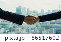 都市を背景に握手するビジネスパーソン