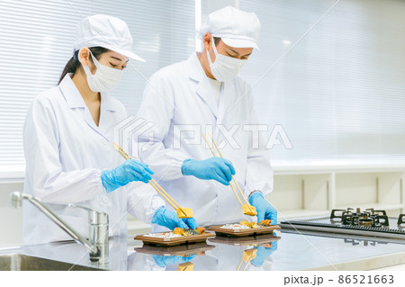 お弁当の盛り付けをする男女(食品加工・手袋) お弁当の盛り付けをする男女(食品加工・手袋) 86521663