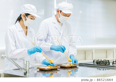 お弁当の盛り付けをする男女（食品加工・手袋） 86521664