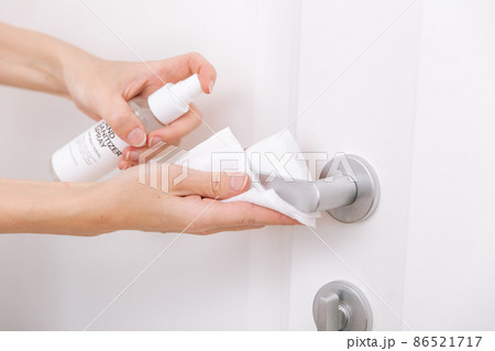 Cleaning white door handles with an antiseptic wet wipe and sanitizer spray. Disinfection in hospital and public spaces against corona virus. Woman hand using towel for cleaning home room door link. Cleaning white door handles with an antiseptic wet wipe and sanitizer spray. Disinfection in hospital and public spaces against corona virus. Woman hand using towel for cleaning home room door link. 86521717