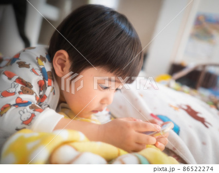 ふとんに寝っ転がってスマホをいじる3歳児 86522274