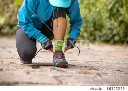 Woman runner tying shoelace on trail Woman runner tying shoelace on trail 86525226
