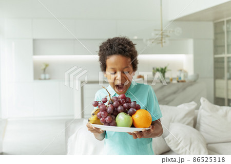 Child holding and eating fruit on white background. Food, diet and healthy eating concept Child holding and eating fruit on white background. Food, diet and healthy eating concept 86525318
