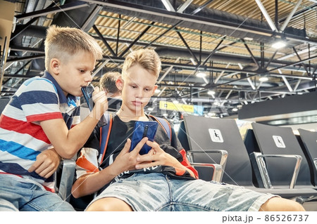 Brothers play games on phones sitting in airport hall 86526737
