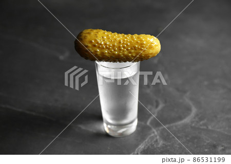 Cold Russian vodka with pickle on black table, closeup 86531199