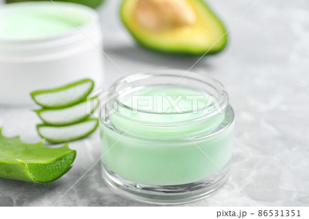 Open jar of cream and cut aloe on marble background, closeup Open jar of cream and cut aloe on marble background, closeup 86531351