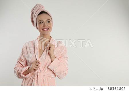 Beautiful young woman in bathrobe on light background. Space for text 86531805